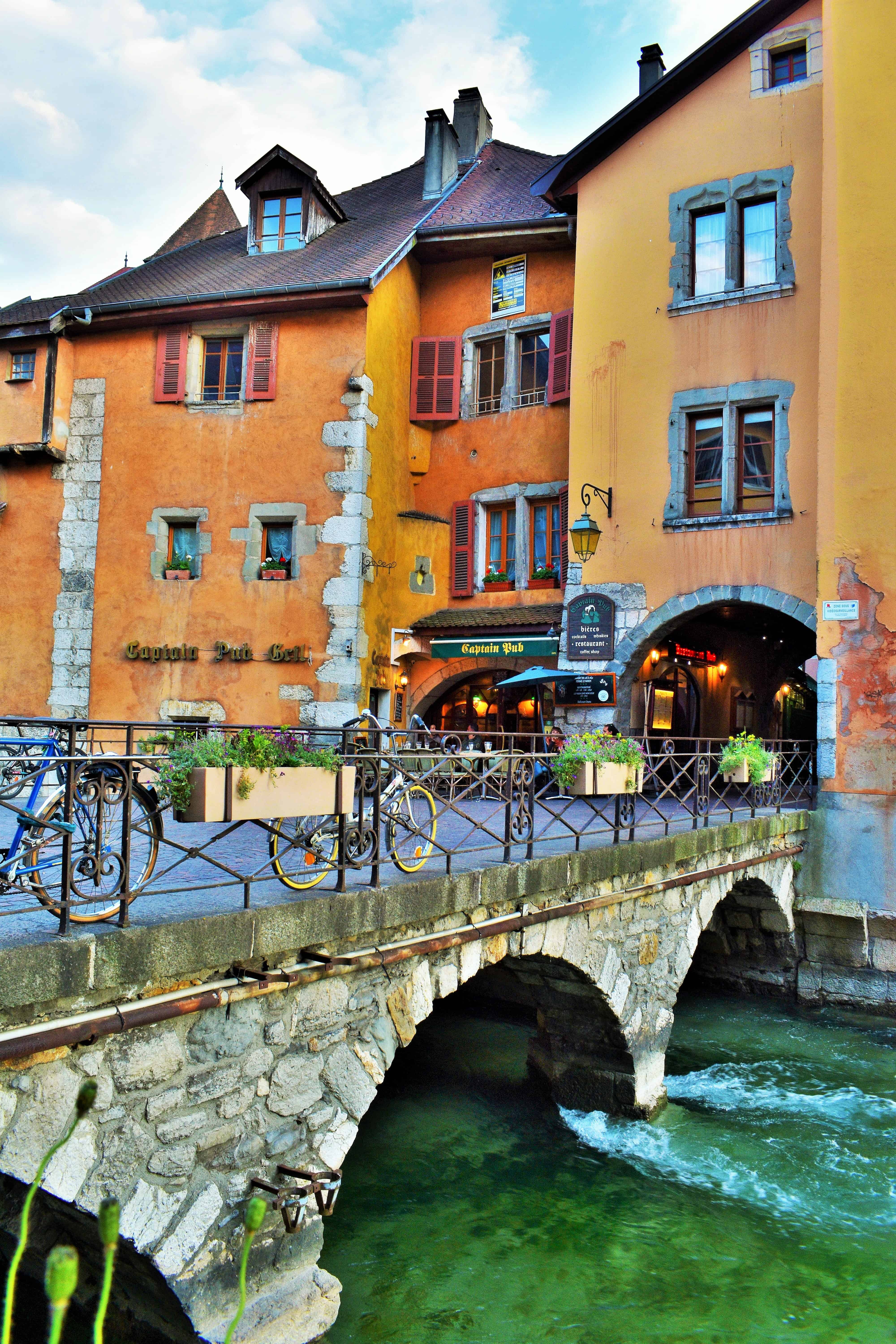 Vertical shot of some orange buildings on a bridge over a canal in Annecy, France