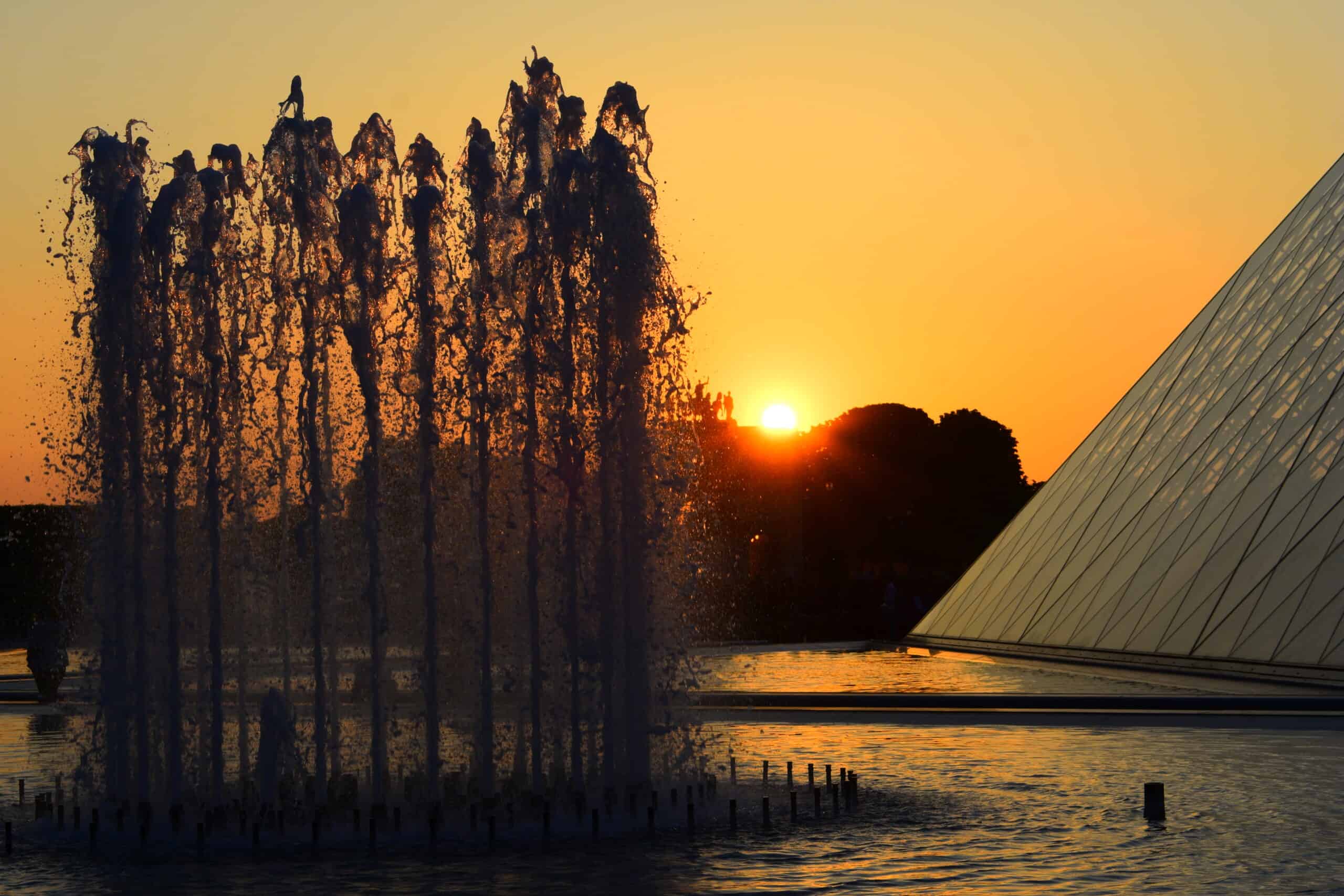 Le Louvre museum and water fountain lit up gold at sunset