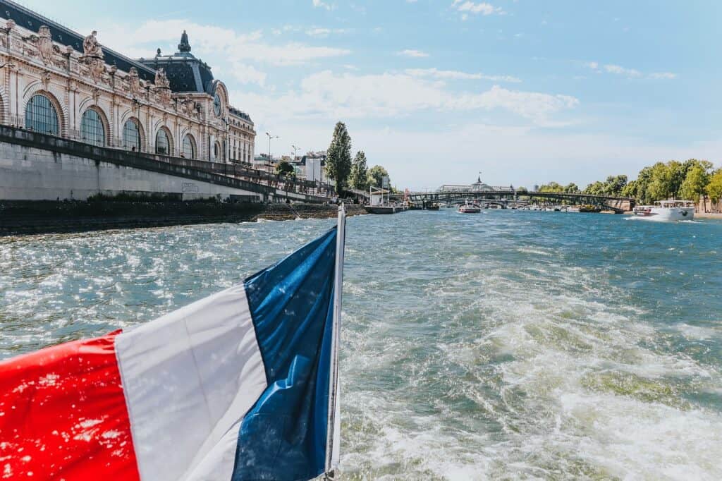 The French flag flying off the back of a boat cruising down the Seine in Paris