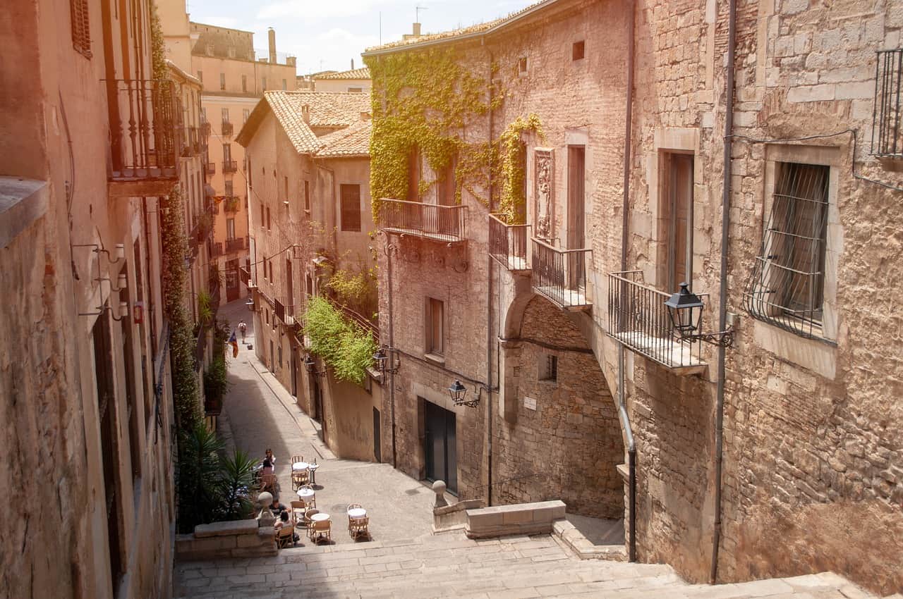 Narrow street full of stairs and brick buildings covered in green vines