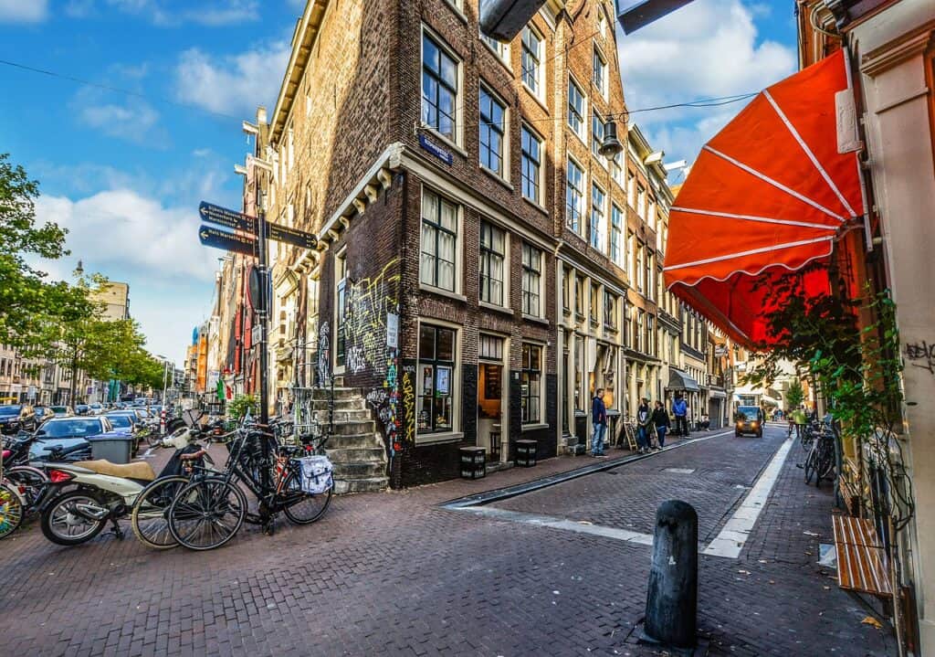 Corner street in Amsterdam with tall, brick buildings and full bike racks