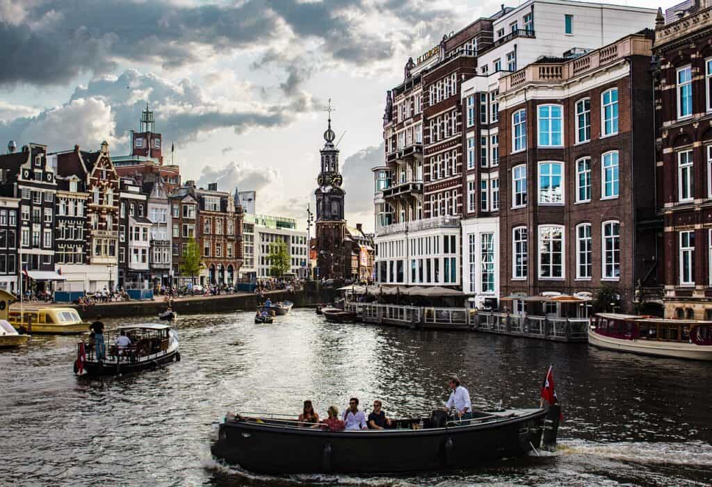 Dark photo of several full boats enjoying rides on the canals in Amsterdam