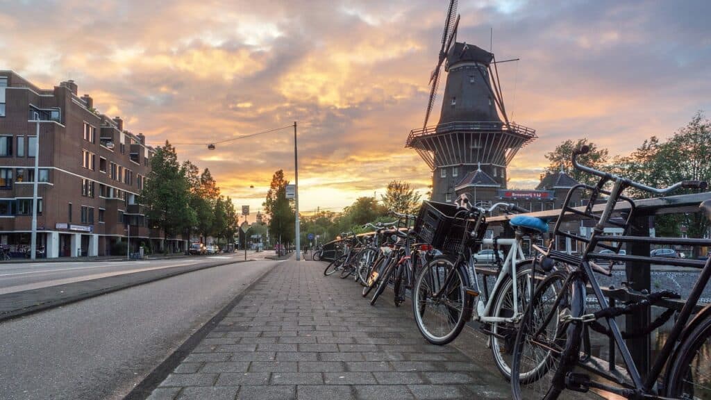 Bicycles locked up to a railing leading to a windmill in Holland