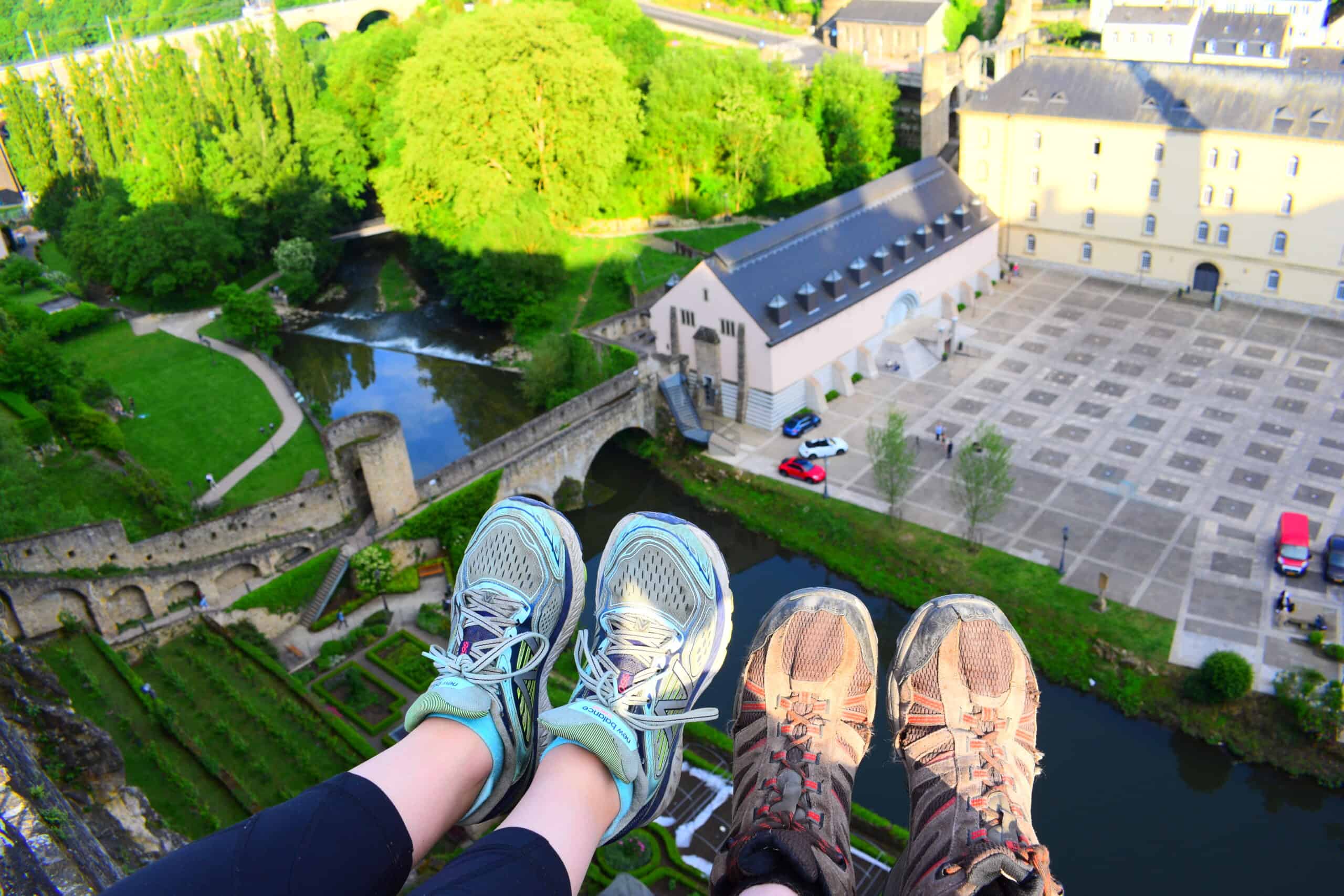 Two sets of feet wearing sneakers overlooking the Bock Casemates in Luxembourg City