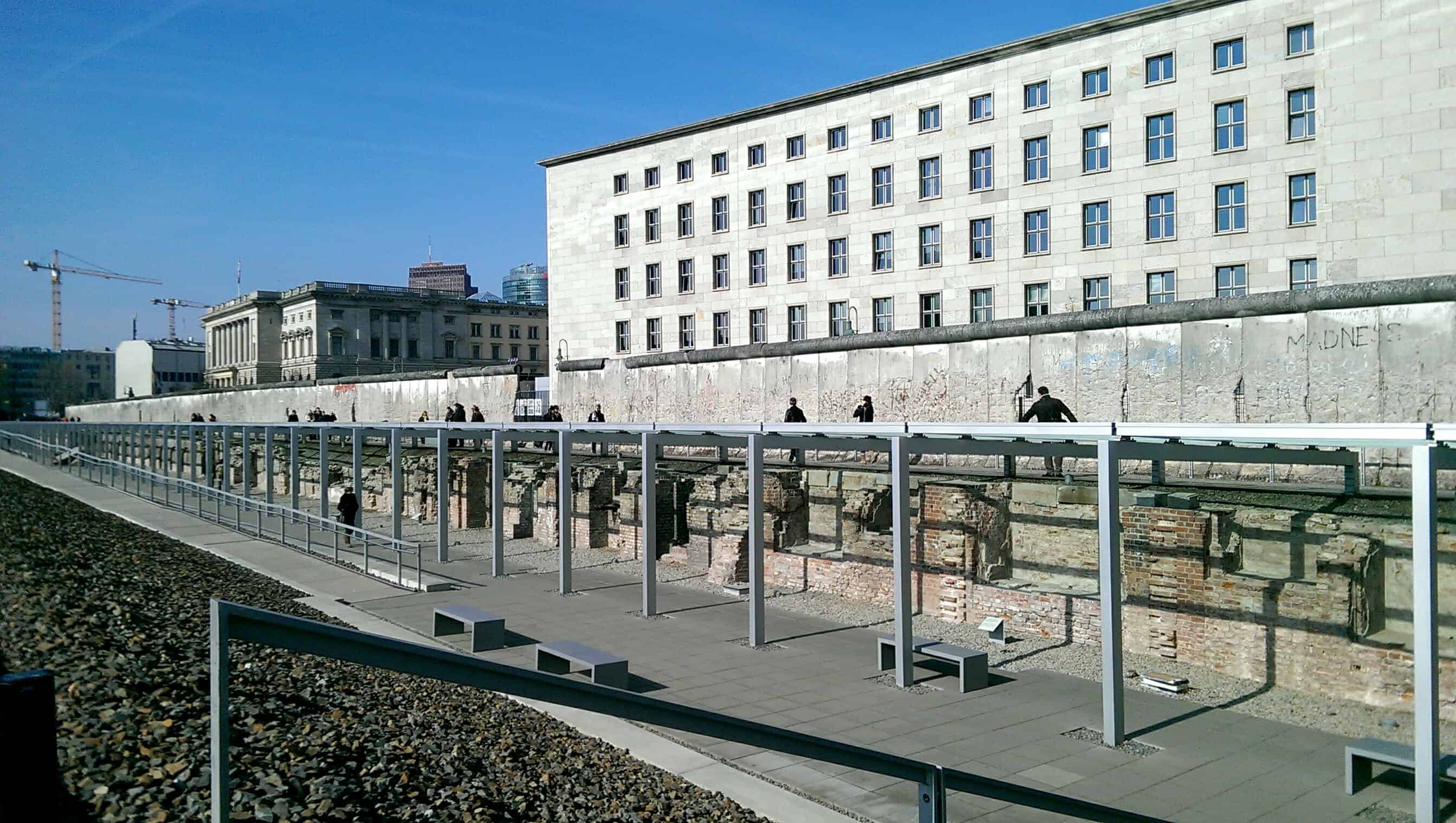 A section of the Berlin Wall with people walking alongside it