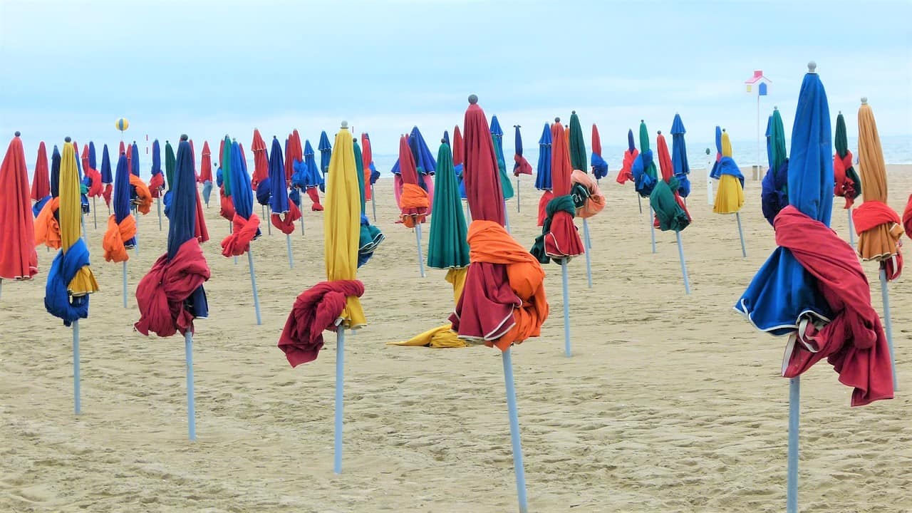 White sand beach with dozens of tied down colorful umbrellas