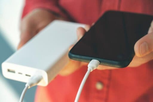Black cell phone plugged into a white battery pack