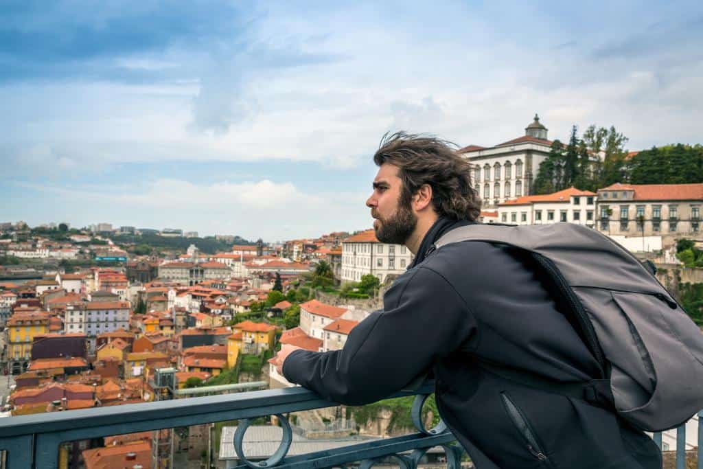 Man with a backpack looking out at Lisbon from a viewpoint