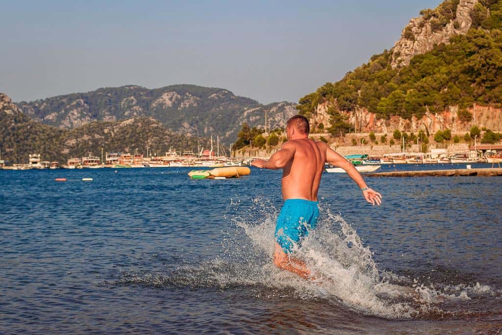 Man in a blue bathing suit running into the ocean