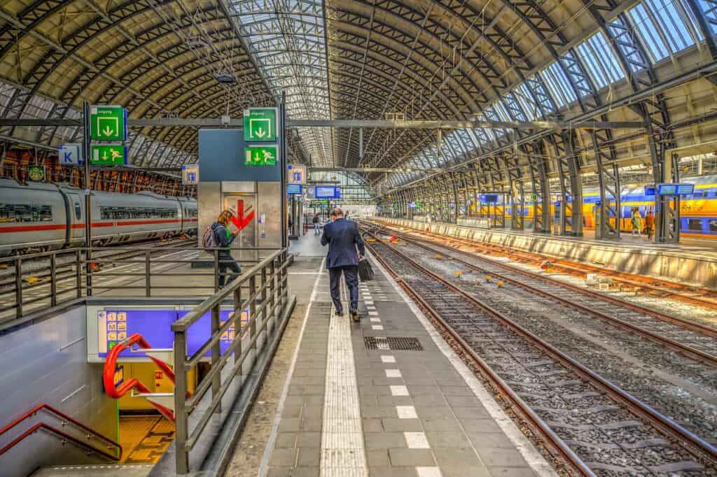 Man in a suit walking inside of a train station next to the tracks