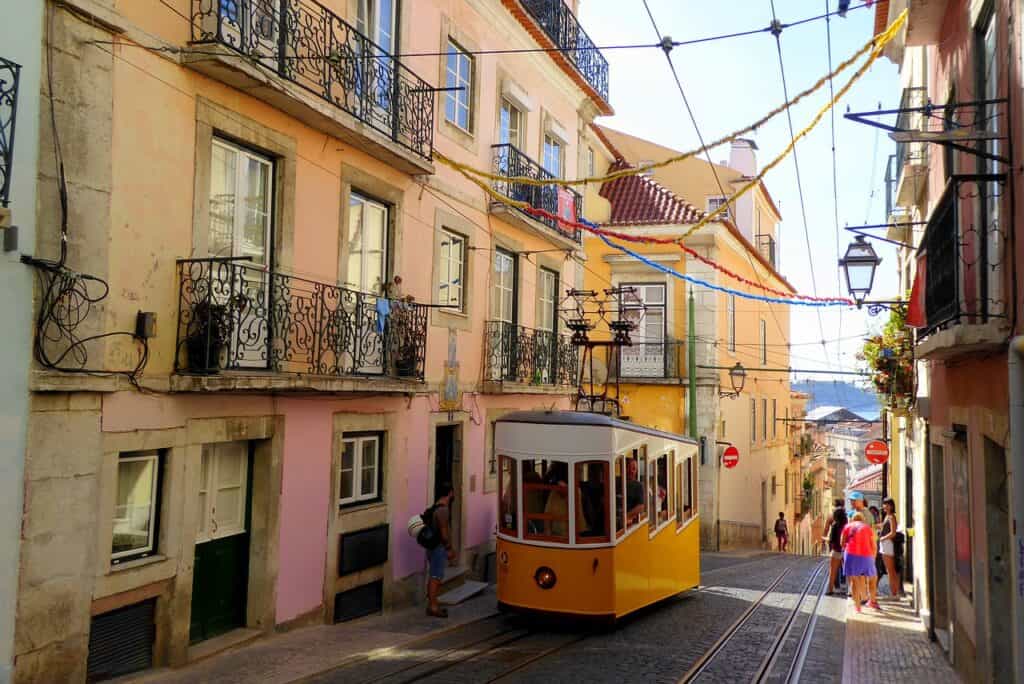Yellow tram on a narrow, hilly street in Lisbon