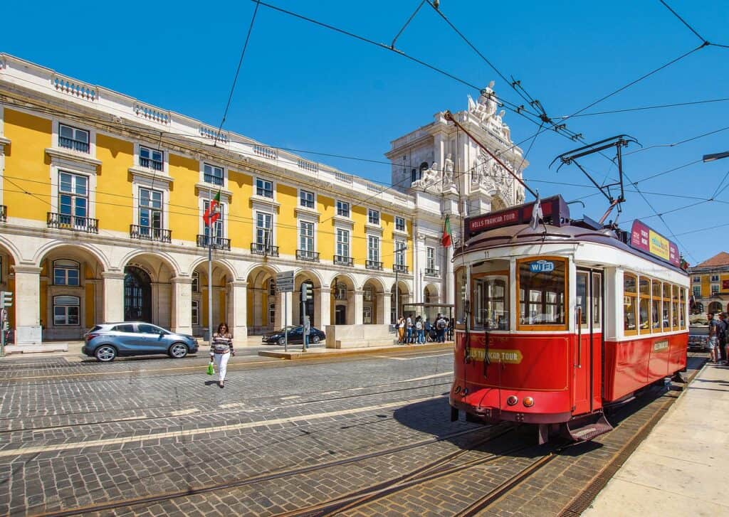 Red tram next to yellow buildings in Lisbon
