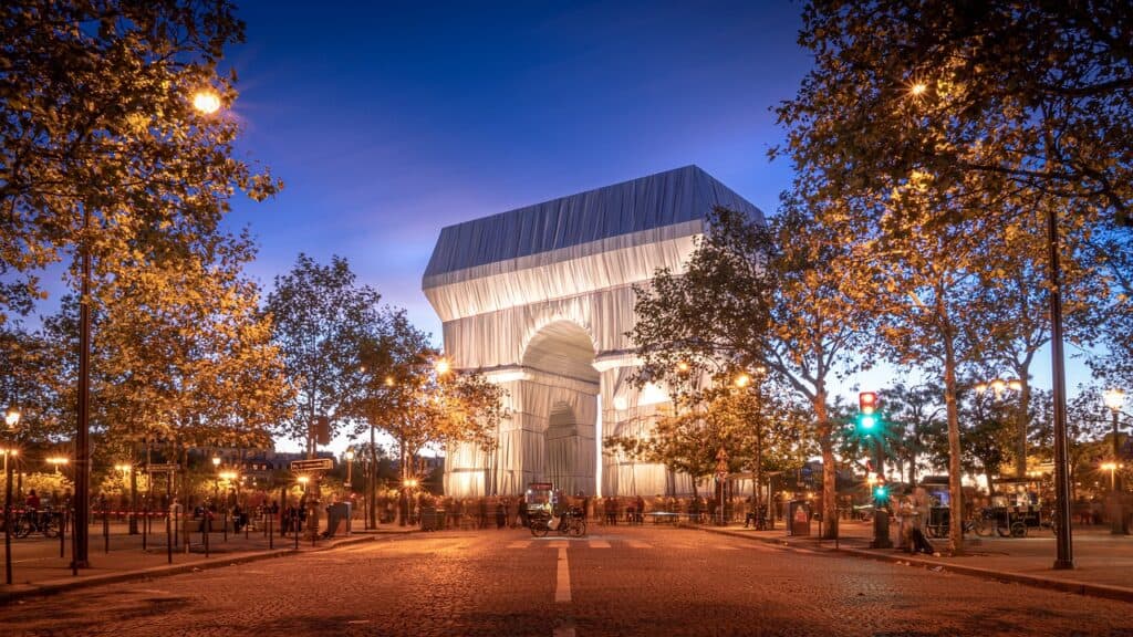 Triumphal arch in Paris after dark surrounded by trees