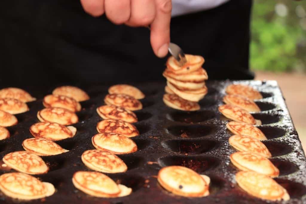 Person flipping mini Dutch pancakes in Amsterdam