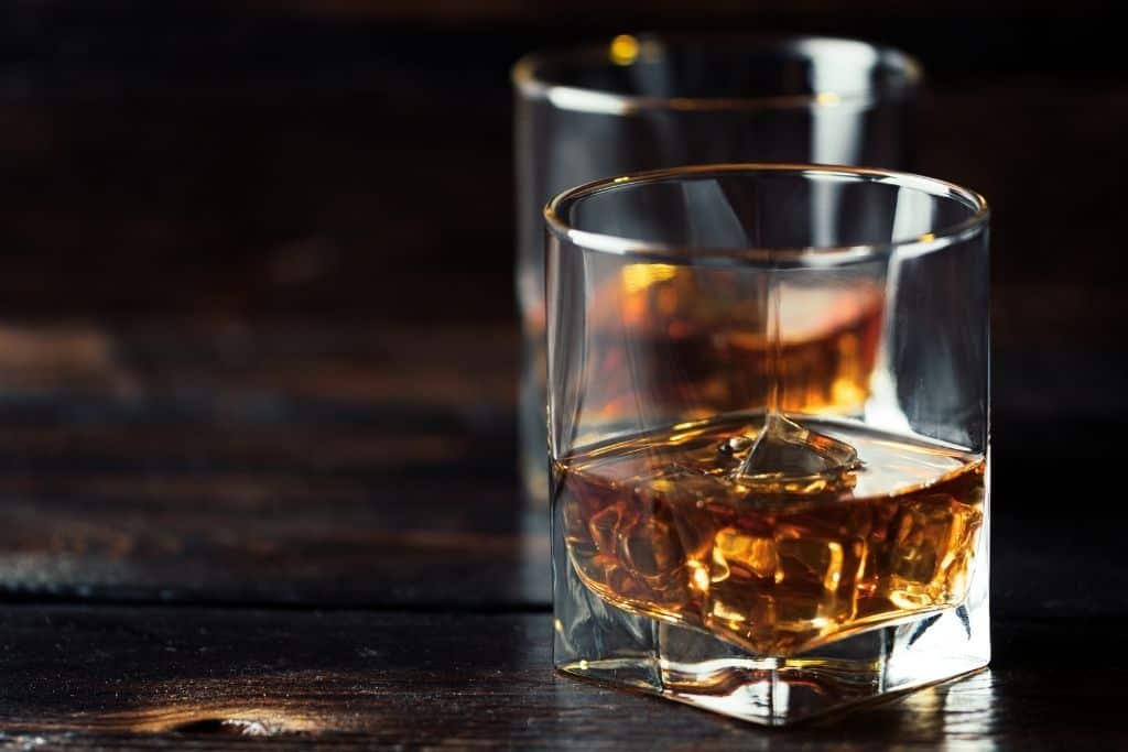 2 half-full whiskey glasses with ice