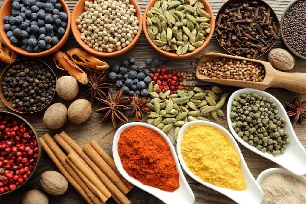 Variety of whole spices in bowls on a wooden table
