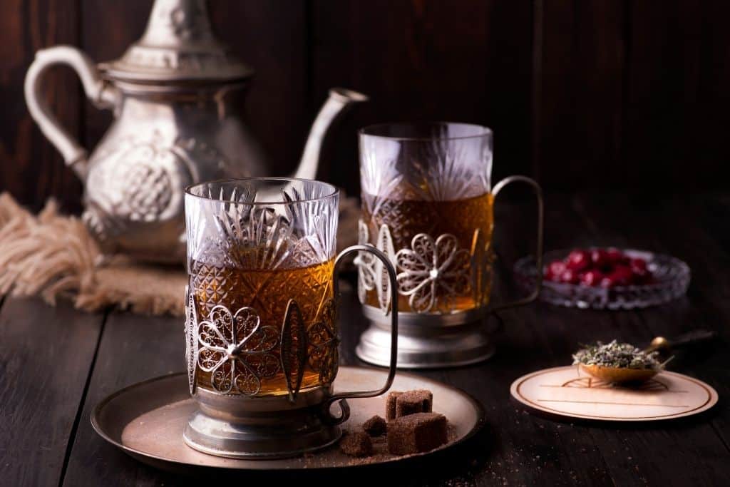 Glass and metal tea set with mugs and a metal pot