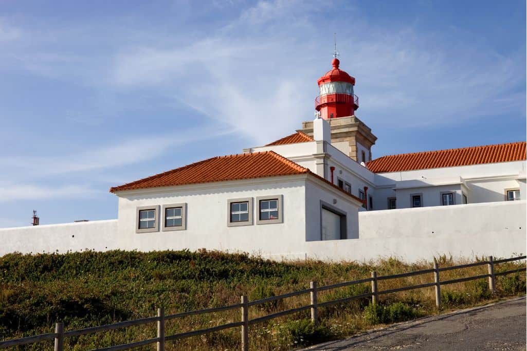 Red and white lighthouse on a hillside in Portugal