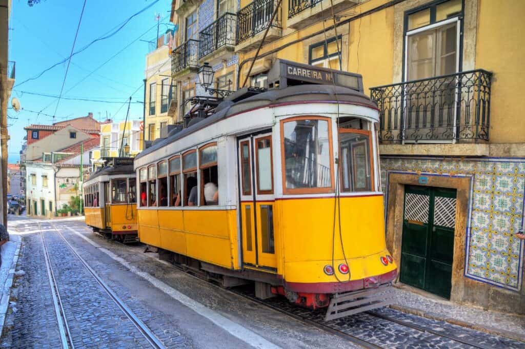 2 yellow trams driving through Lisbon