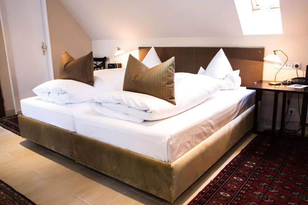 2 twin beds next to each other with fluffed brown pillows and white duvets