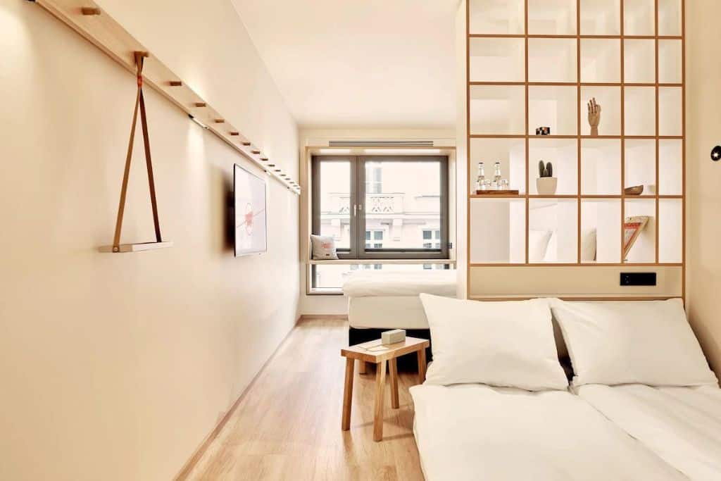 Modern all-white hotel room with a window and small bed