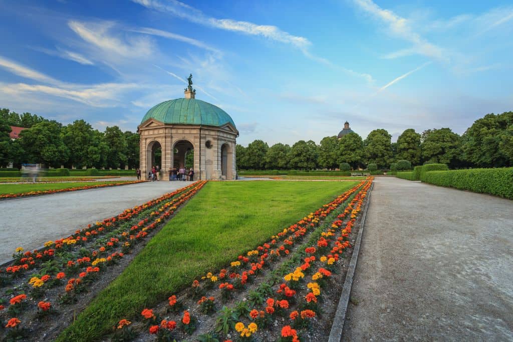 Outdoor gazebo on a manicured lawn with flowers and gravel