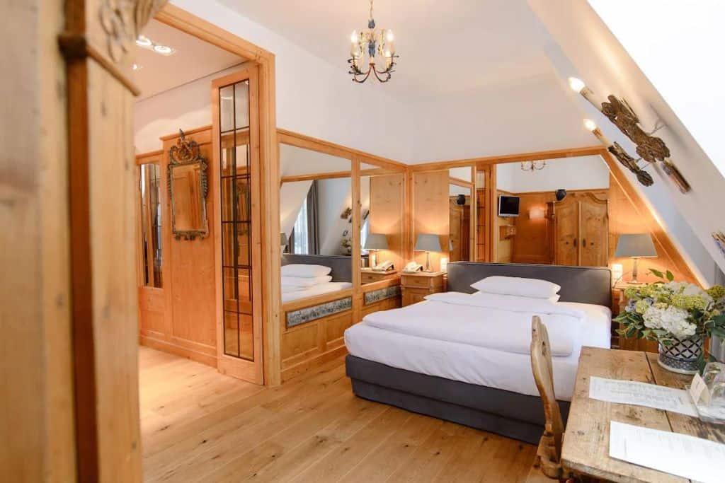 White and grey bed in a wood-heavy hotel room