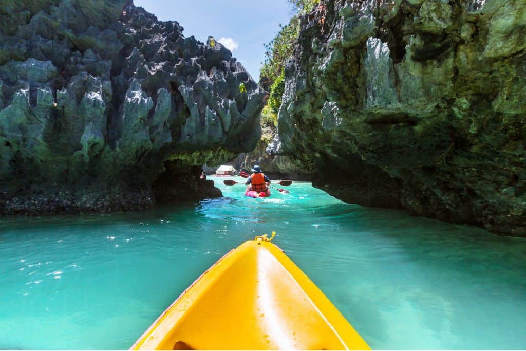 Yellow kayak going through blue waters and rock formations