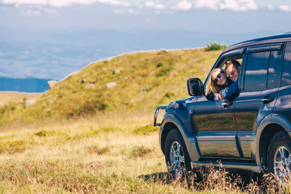 People in a jeep on a grassy hillside