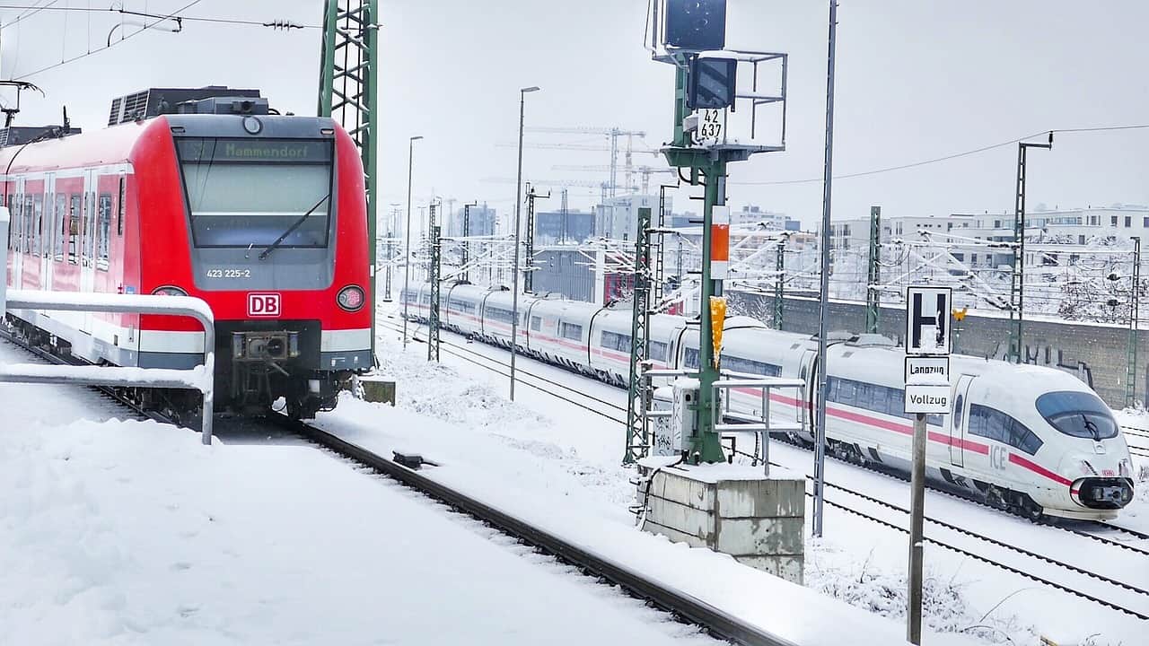 Red trains driving over snowy train tracks
