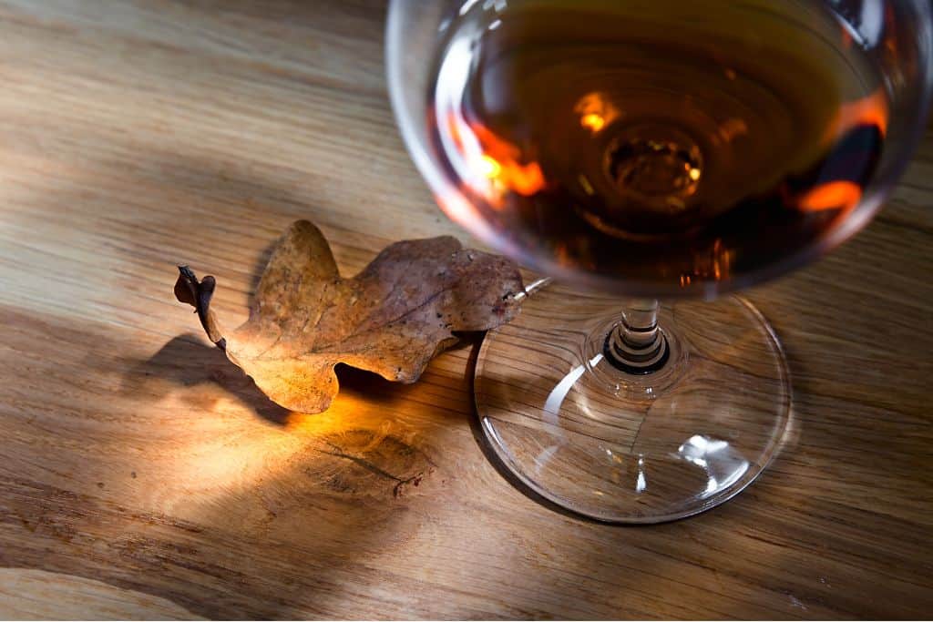 Glass of Unicum, or Hungarian herbal liqueur next to an oak leaf on a wooden table
