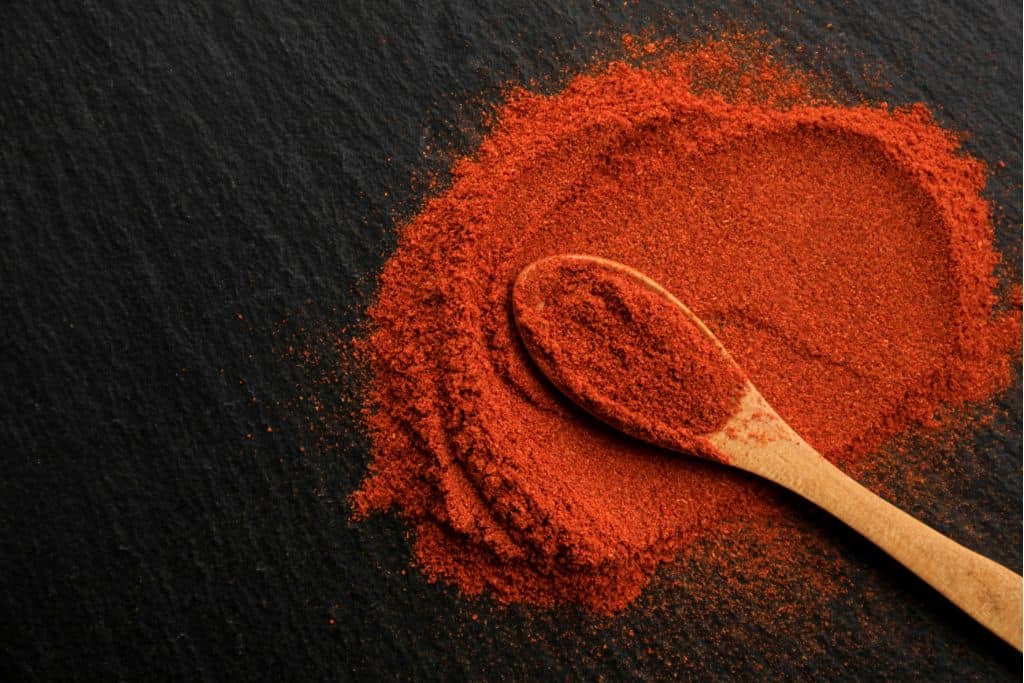 Pile of paprika with a wooden spoon