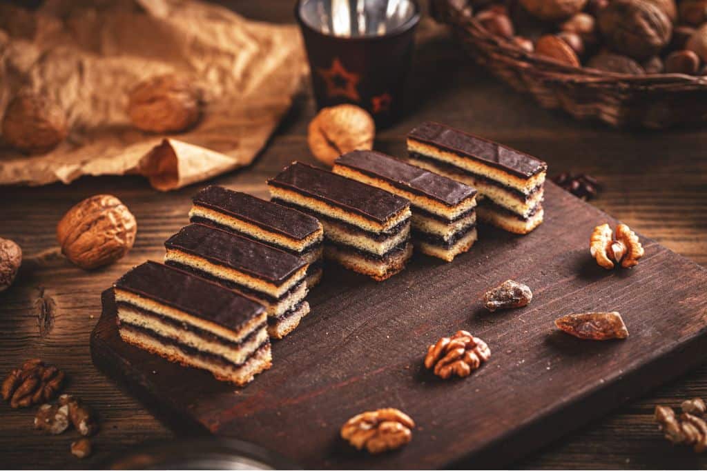 Layered chocolate cakes on a wooden tray surrounded by nuts