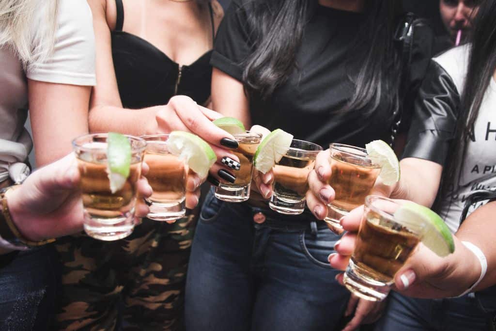 Several people holding shot glasses with limes