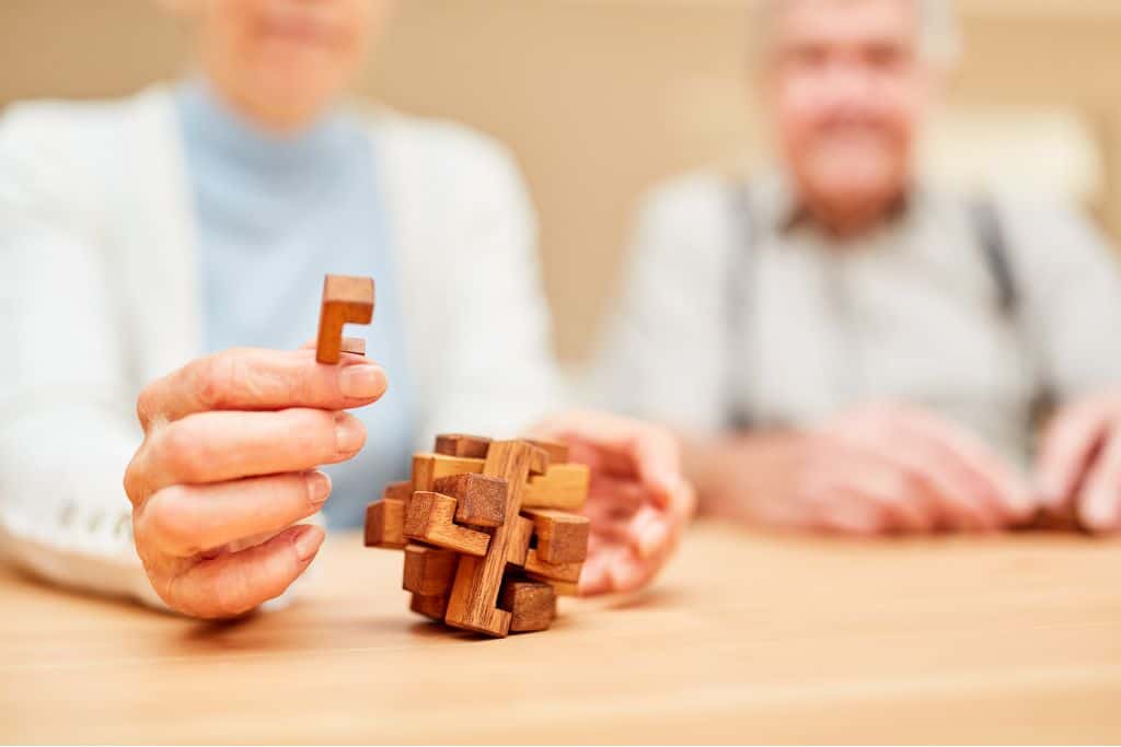 Person holding a piece to a wooden mechanical puzzle
