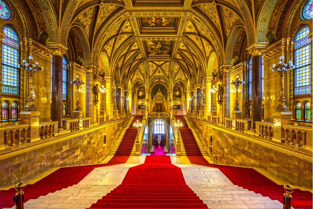 Inside of a very fancy golden hall with red and white carpet