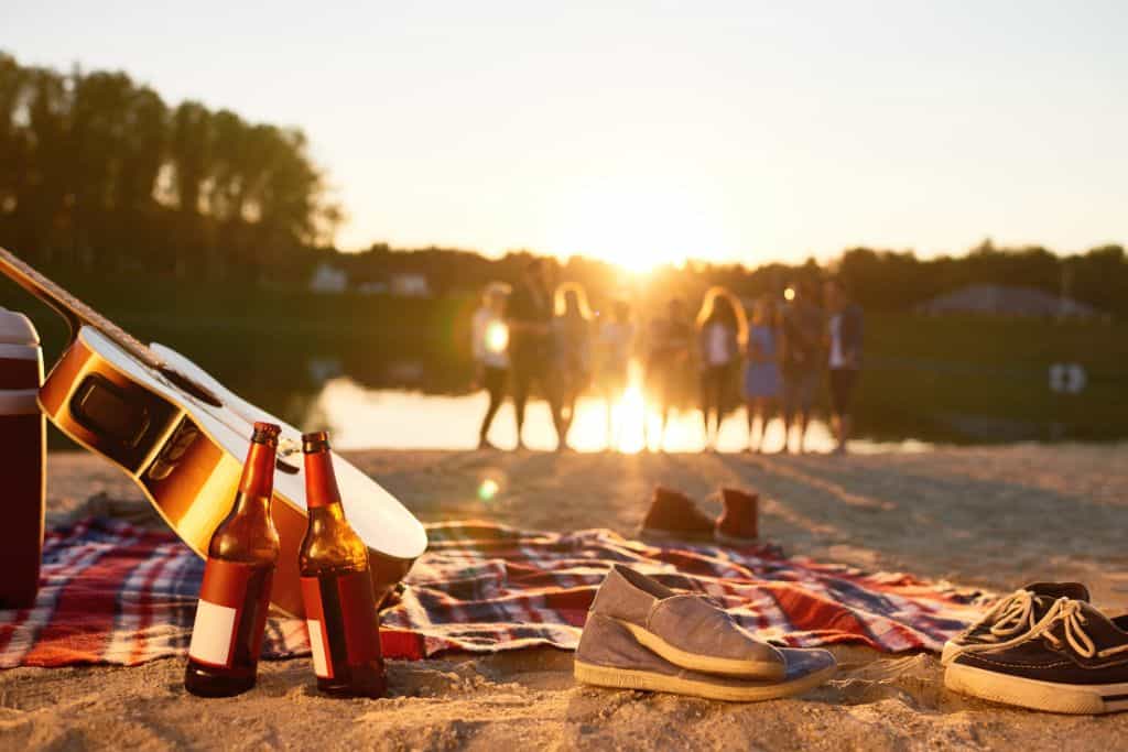 Group of people at a lake with a picnic blanket and some goodies to snack on