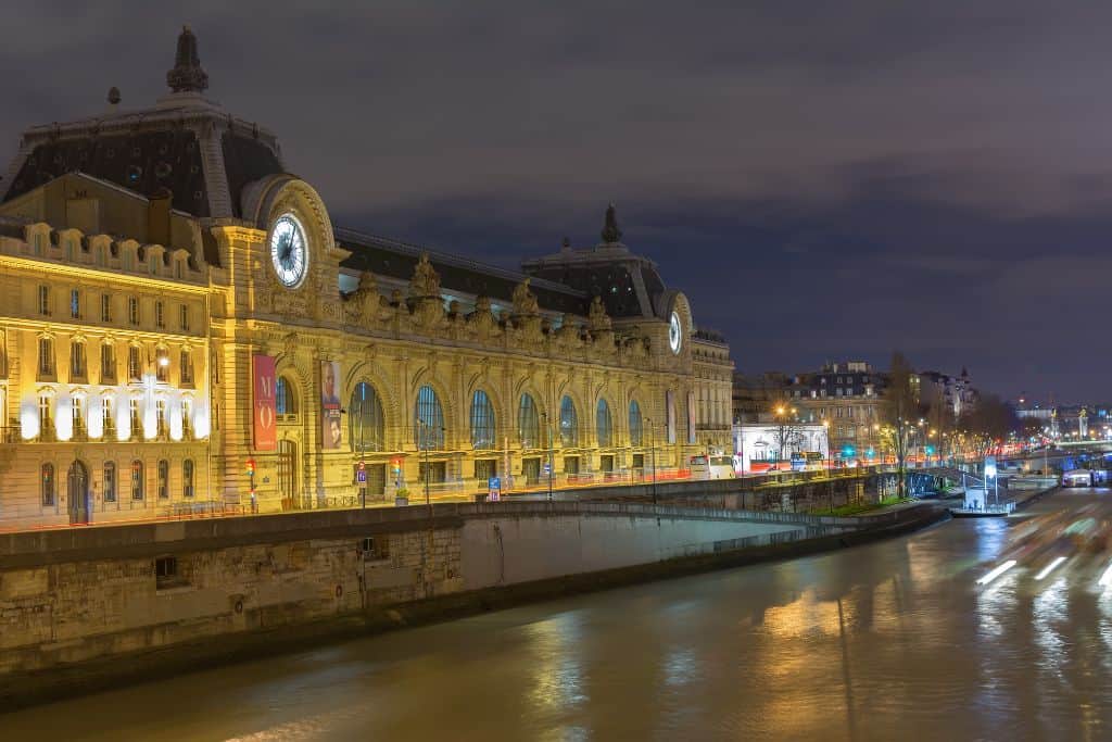 Front of a large building along the Seine at night