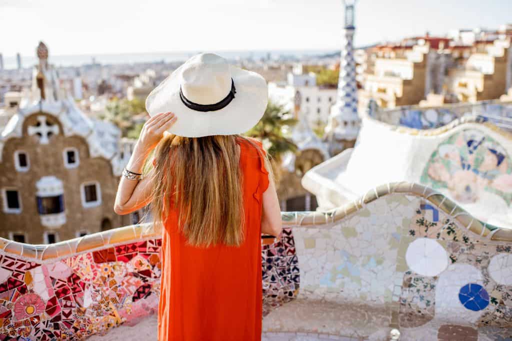Girl in a red dress and sunhat looking out at Barcelona from Park Guell