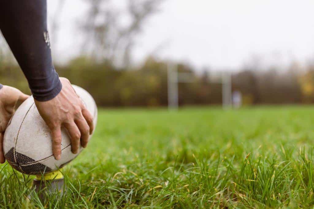 Person holding a rugby ball on a field