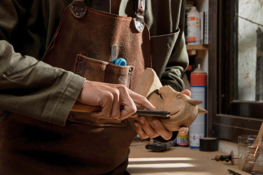 Person carving a wooden horse