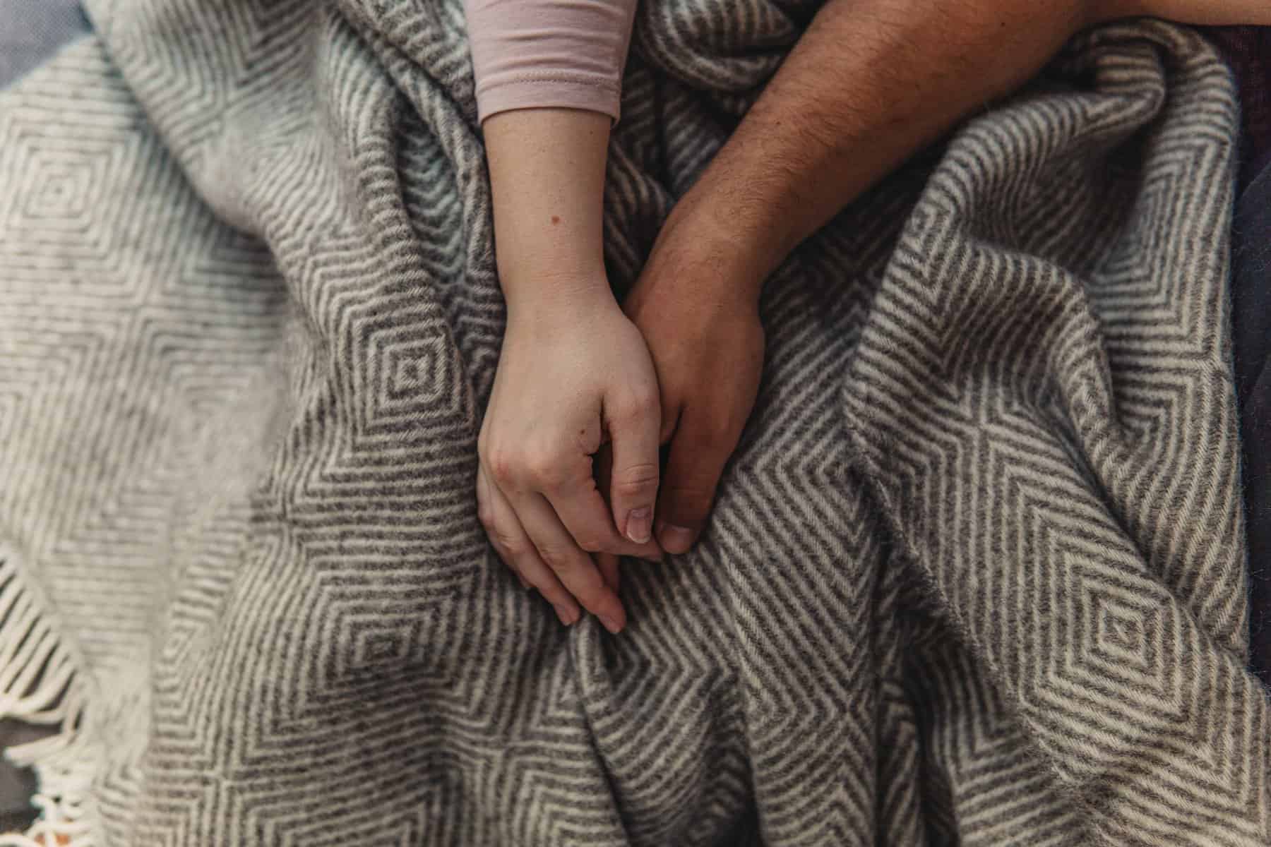 Man and woman holding hands over a wool blanket