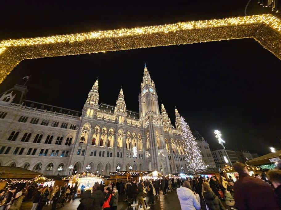 Vienna's Town Hall under a Christmas-decorated frame and surrounded by thousands of people