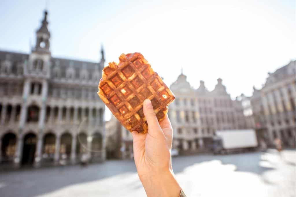 Personal holding a waffle in Belgium