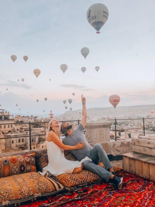 People in Turkey looking up at colorful hot air balloons while on a hotel balcony