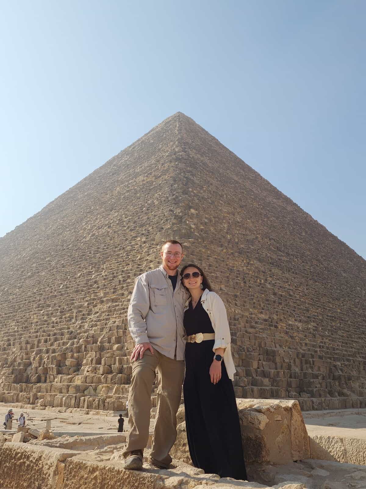 Emily & Sean Concannon standing in front of the Pyramids of Giza in Egypt on a sunny day