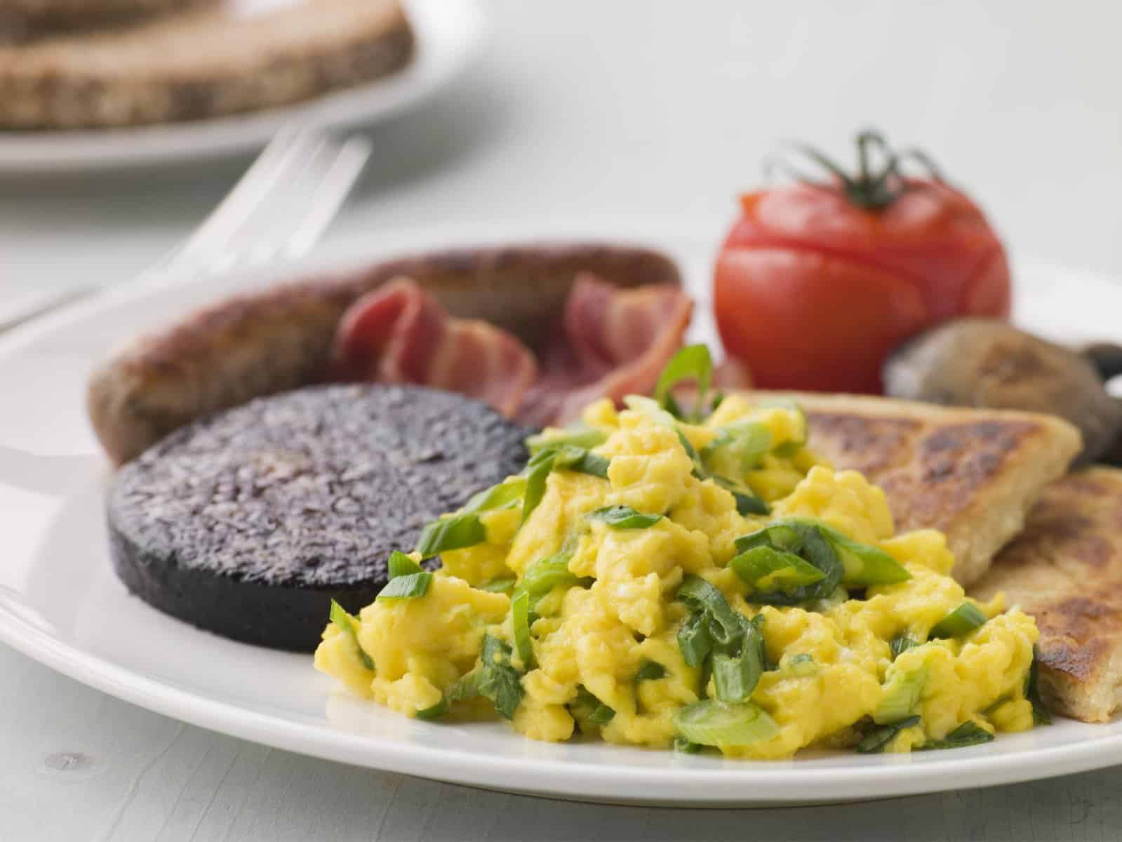 Plate of classic Irish breakfast with tomatoes, eggs, bangers, and blood pudding