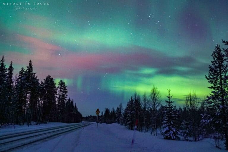 Northern lights in Northern Finland over a snowy road
