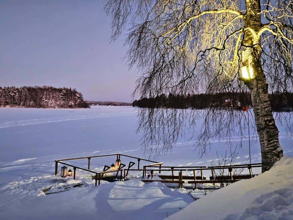 Wooden walkway going down to a frozen river with a cutout where people can do a polar plunge in Rovaniemi, Finland