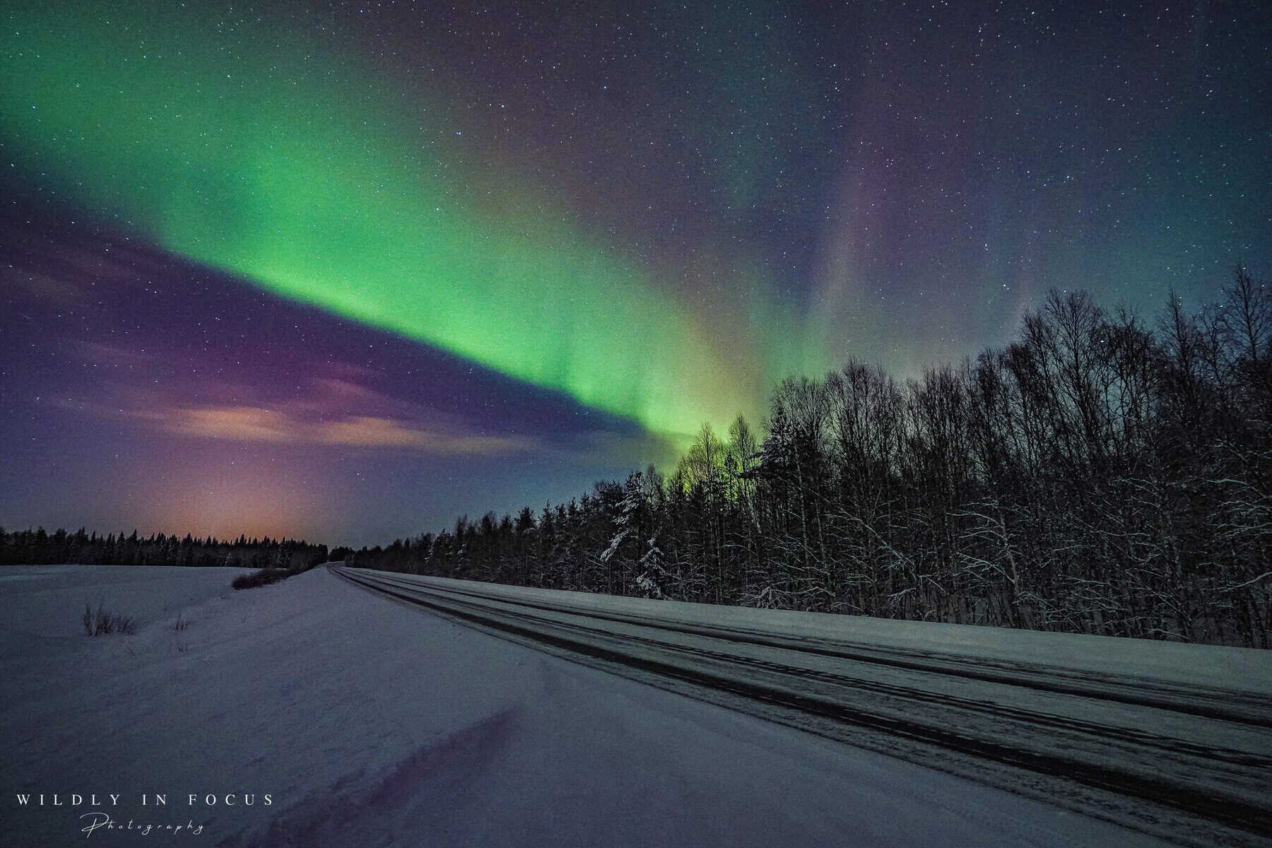 Northern lights over a snowy road in Rovaniemi, Finland
